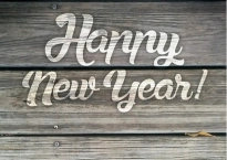 Image shows a wooden fence with the words Happy New Year! written on it in fat white letters.