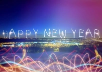 Photo shows a city skyline in lights. The words Happy New Year appear in a font that looks like it's made of light across the horizon.
